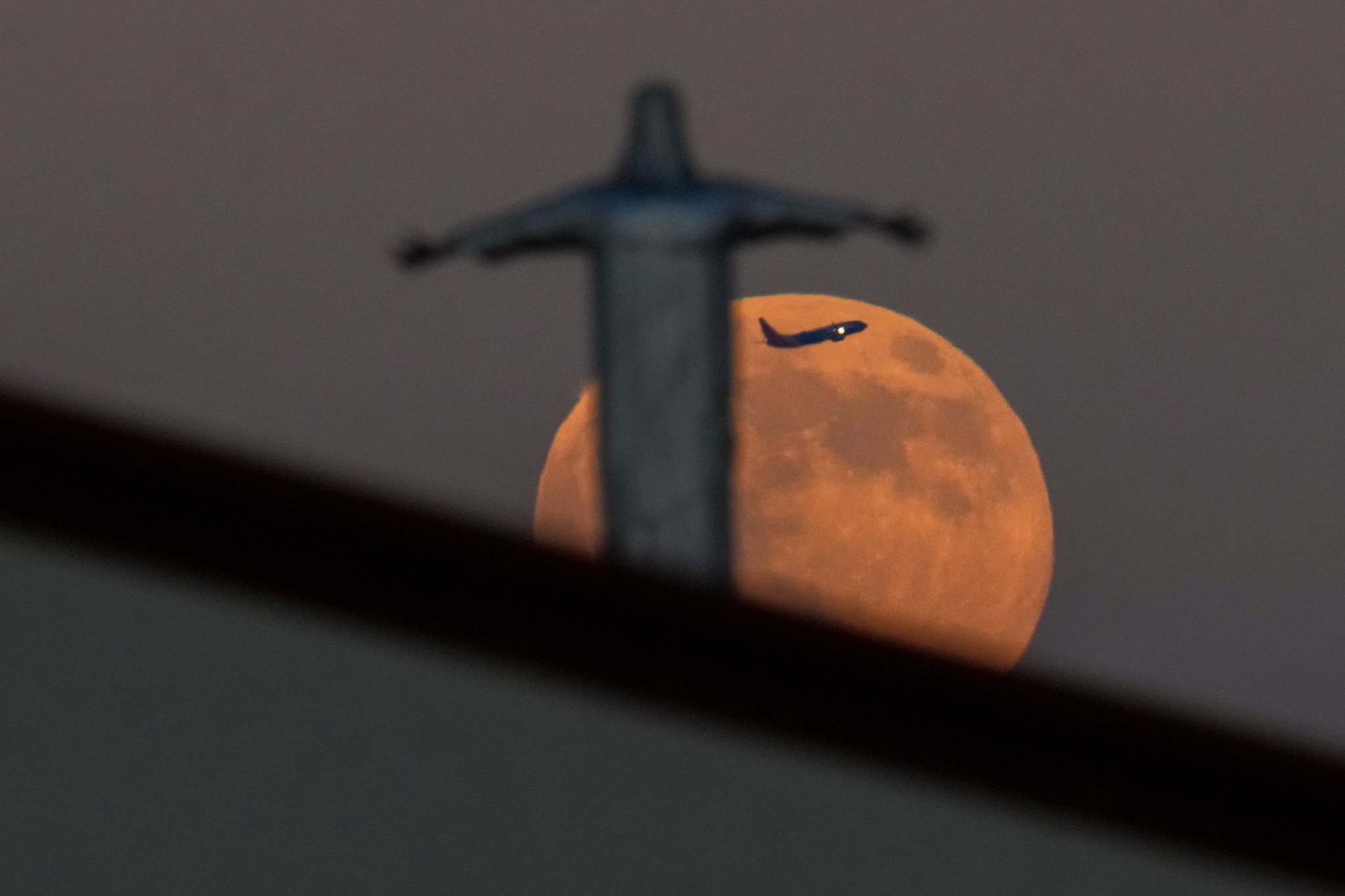 A Southwest Airlines plane takes off from Dallas Love Field Airport, appearing between the Harvest Supermoon and a statue of Jesus Christ atop Iglesia Luterana Santa Maria de Guadalupe in Irving, Texas, on Monday, October 6, 2025. (Image: AP Photo/Julio Cortez)