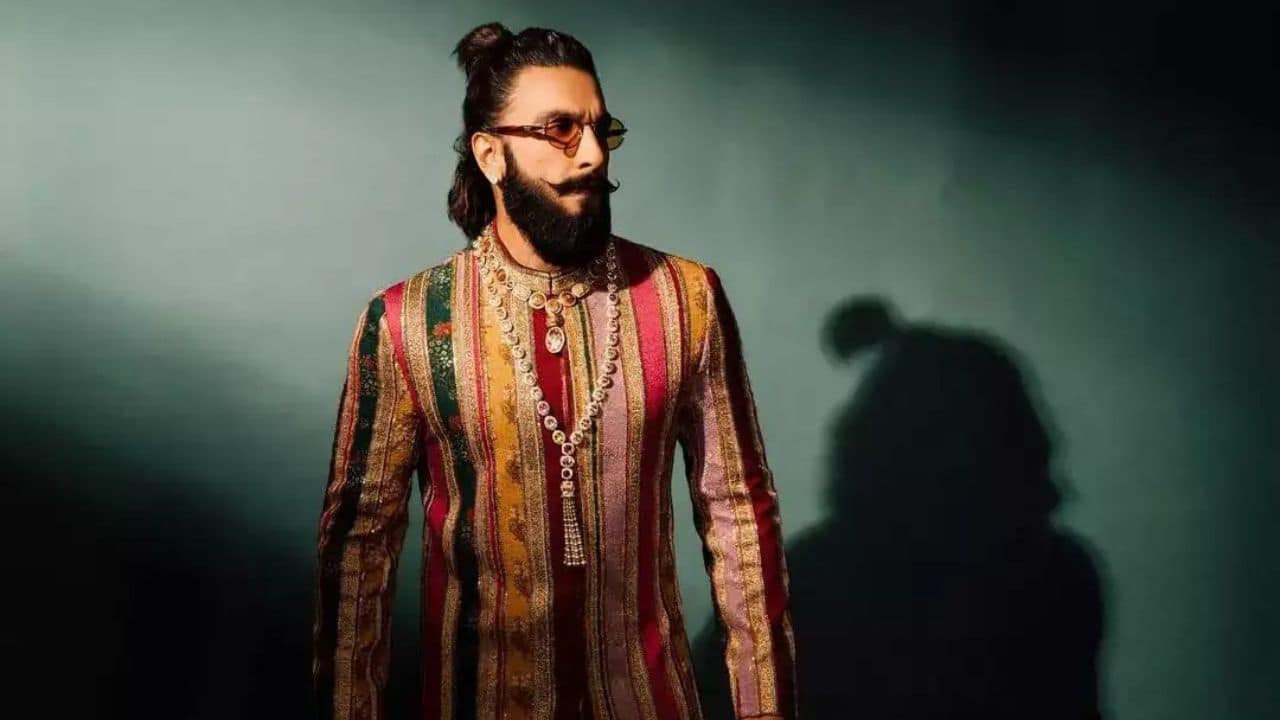 Vibrant Colors, Vibrant Energy Wearing a multicolored kurta with vertical stripes in cream, brown, green, yellow, red, and peach colors, Ranveer Singh welcomed a lively festive vibe. Wearing golden shiny boots, matching pajamas, with layered heavy chains, Ranveer added a playful, lively twist to his royal ethnic look ideal for festive occasions.
