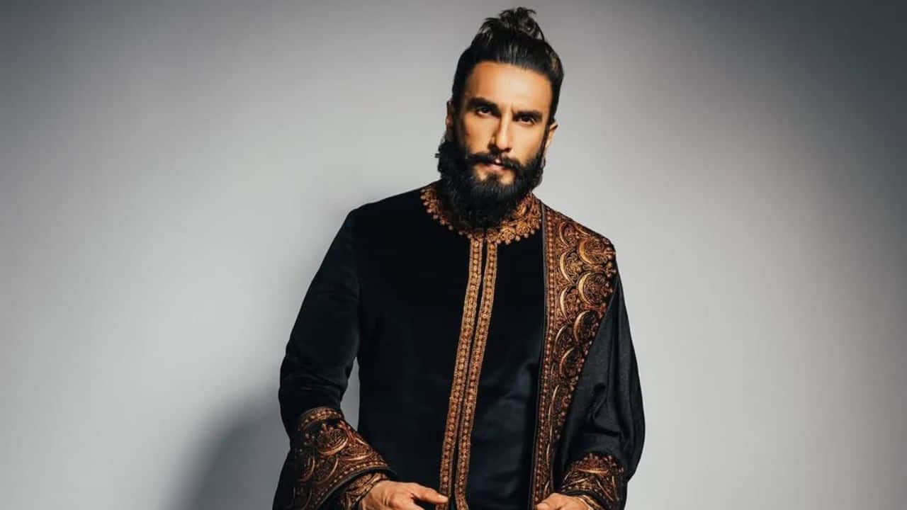 Royal &amp; Black in Every Stitch Ranveer Singh in a black velvet sherwani kurta with brown and golden embellishments on the sleeves and center which gives a royal and elegant vibe. This look of the actor reflects sophistication and festive charm with an embroidered shawl. The actor's outfit fits perfect for making a dapper, classic statement at the festivities.