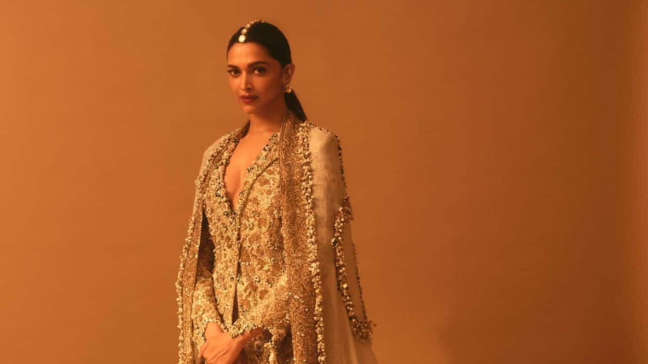 Royal gold &amp; ivory outfit The actress looks like royalty in this dramatic ivory and gold ensemble, featuring a heavily embellished floor-length jacket and matching pants, topped with a flowing, sheer cape. Her striking diamond and gold maang tikka completes the majestic look.