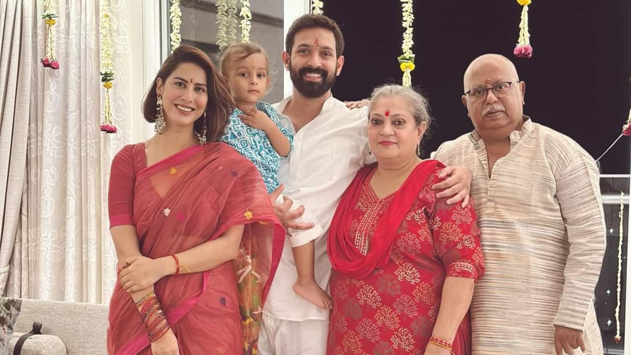 Vikrant, Sheetal, Vardaan, and Vikrant's parents are all included in this photo, making it a full family portrait full of affection and custom. As they celebrate Diwali, the Massey family stands close to one another, wearing coordinated red and cream hues that exude joy and unity. The festive, cosy ambiance is further enhanced by the lights and garlands in the background.