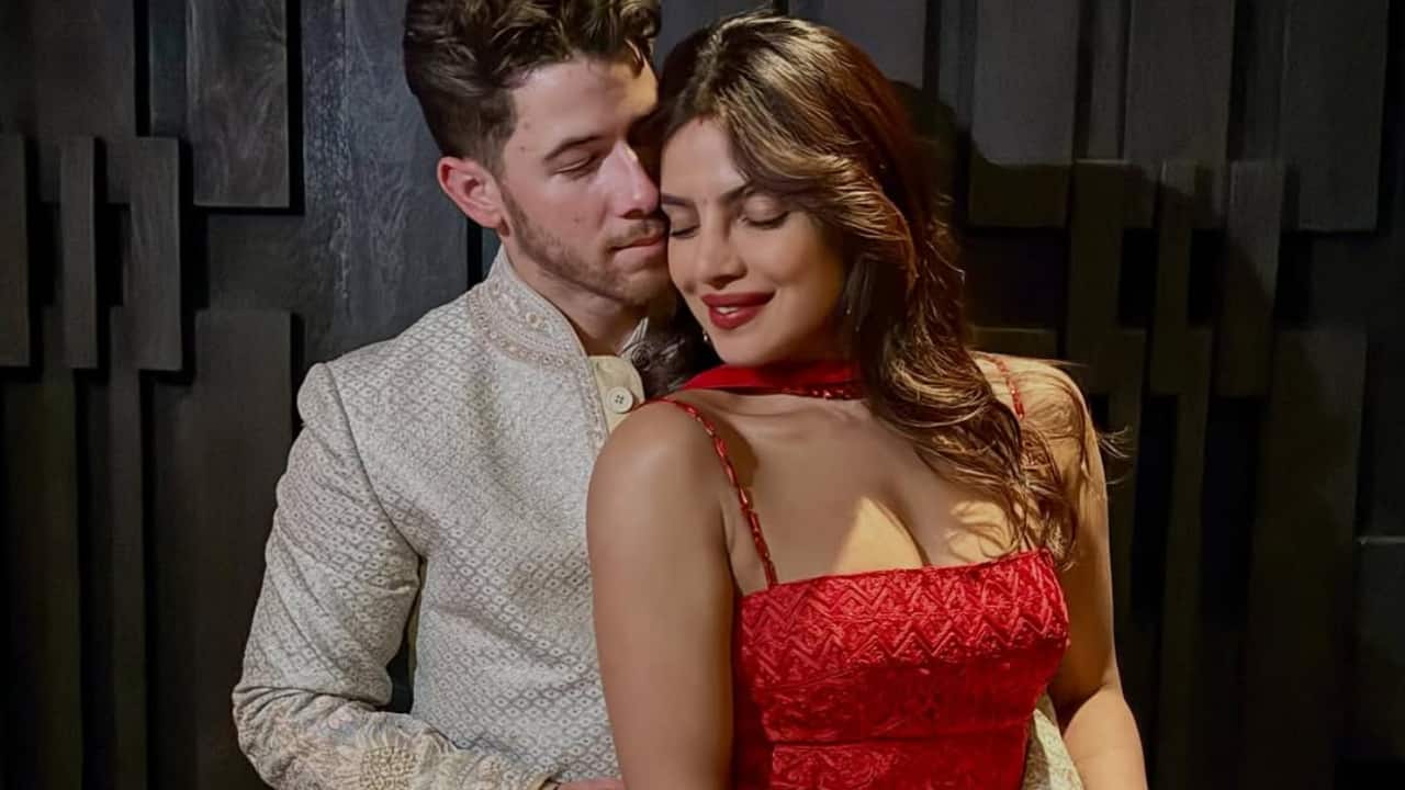 Priyanka Chopra and Nick Jonas radiate warmth in coordinated festive outfits. Priyanka stuns in a red embroidered ensemble, while Nick complements her in an ivory sherwani. The couple’s quiet embrace reflects a tender celebration of love, light, and tradition — perfectly blending Bollywood elegance with New York intimacy.