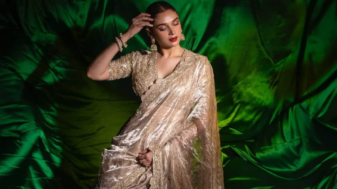 Golden Tissue Lehenga Aditi wore a golden tissue lehenga and a blouse that was heavily embellished, embodying royalty. She chose to wear bold red lips, accessorised her ensemble with rings, kadas, and heavy jhumkas, and wore her hair in a sleek bun.