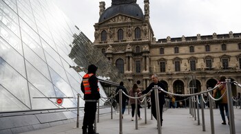 A private security guard patrols in the courtyard of the Louvre pyramid designed by Chinese-US architect Ieoh Ming Pei, in Paris, on November 3, 2025. (Photo by Julie SEBADELHA / AFP)