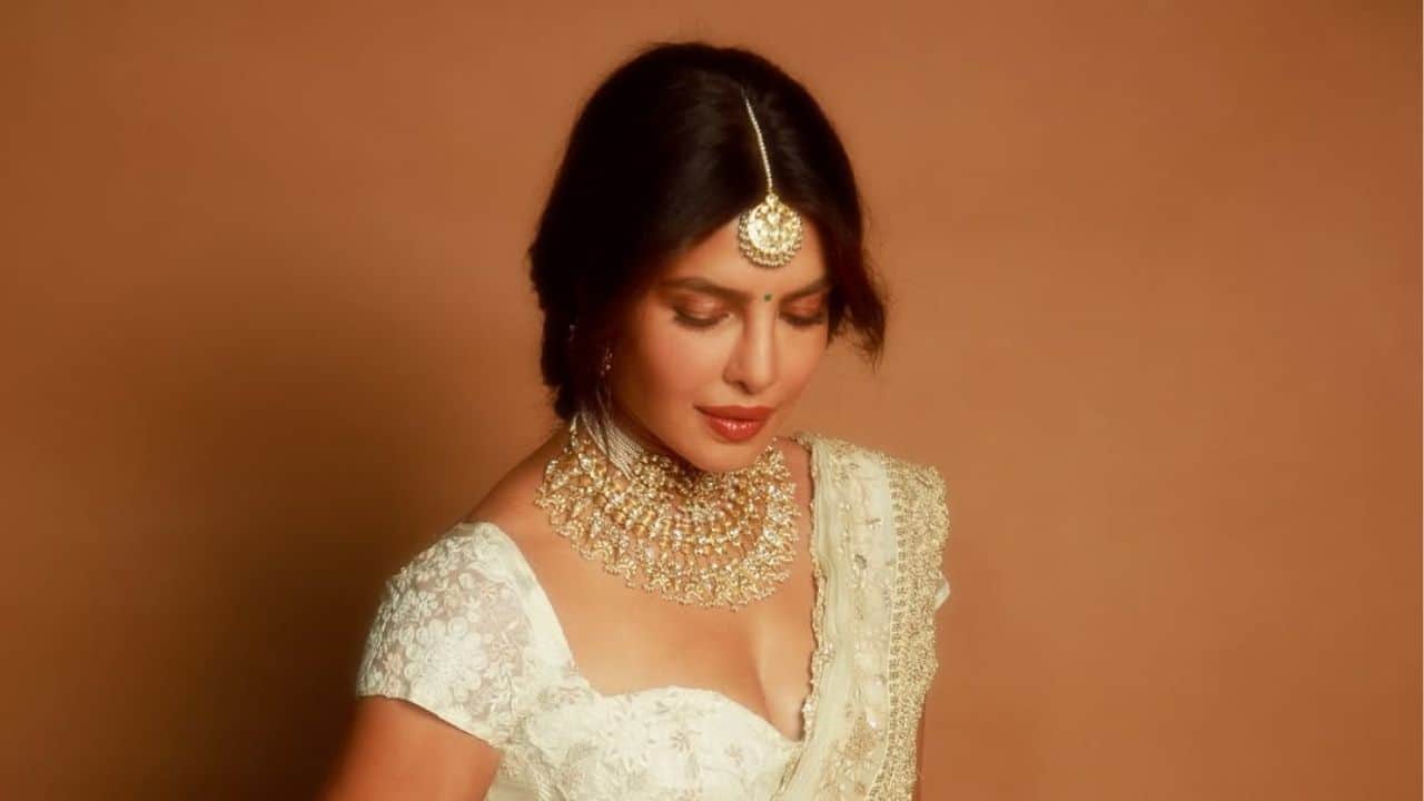 Priyanka Chopra appears calm and divine in this striking picture, her eyes softly lowered in a graceful moment. She accessorises her look with a delicately designed blouse and an intricately embroidered ivory saree, while her maang tikka and layered gold choker give her a regal appearance.