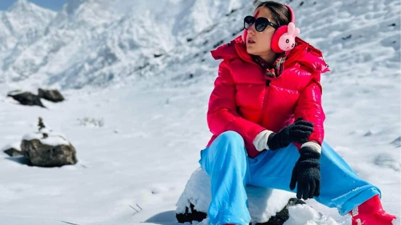 Sara Ali Khan Sara brings a very bubbly energy to winter fashion with a bold, colorful outfit featuring a hot pink puffer jacket and a matching cap, a saffron scarf, and light blue joggers paired with pink boots. The look is cheerful, vibrant, and full of personality perfect for a snowy getaway or a fun day in the mountains. This makes Sara’s winter wear look as joyful as her spirit. 