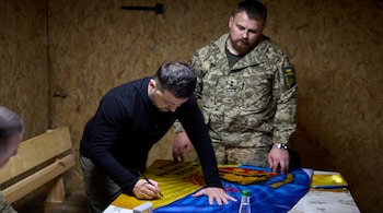 Ukraine's President Volodymyr Zelenskiy signs a flag of the 65th Separate Mechanized Brigade 'Velykyi Luh' while he visits their command position at a front line, amid Russia's attack on Ukraine, in Zaporizhzhia region