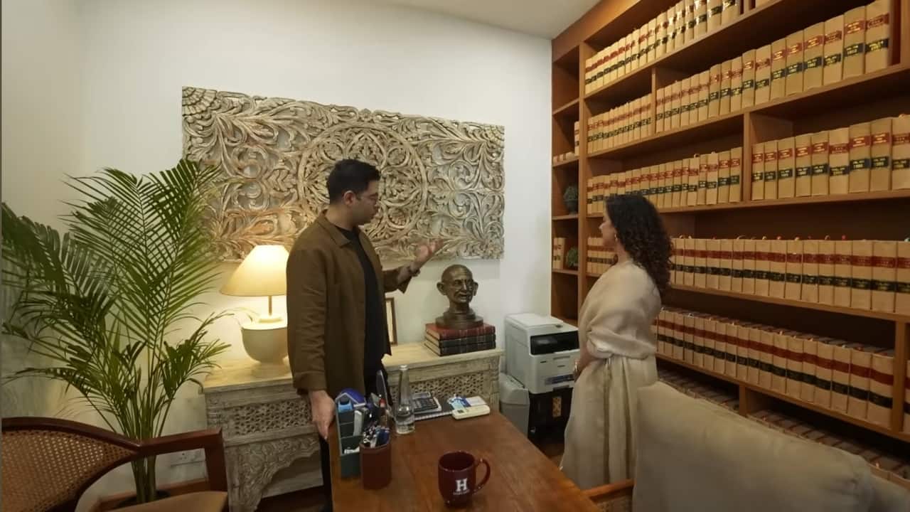 <strong>Books, tables, and lamps:</strong> While his office may not be huge, it has been beautifully designed with wall shelves, a console with a table lamp, and floor plants. The books grab attention not only for being too many, but also for how neatly they have been organised in the space. (YouTube/@curlytalesdigital)