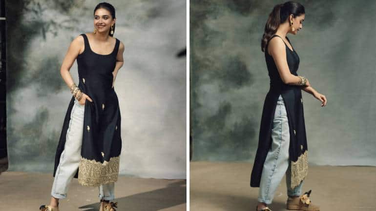 <strong>Style a black kurta with denim</strong><br />Keerthy rocked a long black kurta by the label The Whole Nine Yards. The sleeveless shirt featured a giant motif border and subtle mango buttis that added a bit of glitz. It was paired stylishly with faded, rolled-up denim. Her beige shoes added a sporty touch, while her earrings and stack of bangles brought in that boho-chic feel.