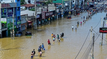 People wade through a flooded street after heavy rainfall in Wellampitiya on the outskirts of Colombo on November 30, 2025. AFP