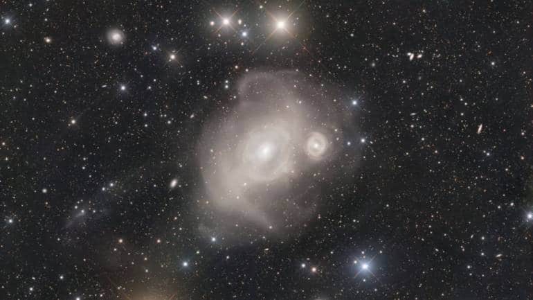 December 4: Galaxies in the Furnace shows massive elliptical galaxy NGC 1316 interacting with smaller NGC 1317. Star streams loop outward, evidence of cosmic collisions. Dust lanes reveal past mergers. Light from their encounter reached Earth 100 million years ago. Located in the Fornax cluster, NGC 1316, also called Fornax A, is a bright radio source extending far beyond the field-of-view. (Image: Simone Curzi/ShaRA Team) December 4: Galaxies in the Furnace shows massive elliptical galaxy NGC 1316 interacting with smaller NGC 1317. Star streams loop outward, evidence of cosmic collisions. Dust lanes reveal past mergers. Light from their encounter reached Earth 100 million years ago. Located in the Fornax cluster, NGC 1316, also called Fornax A, is a bright radio source extending far beyond the field-of-view. (Image: Simone Curzi/ShaRA Team)