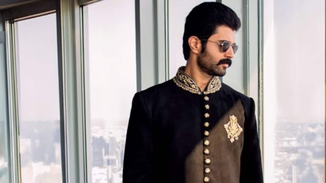 Midnight Black Bandhgala Vijay sported a rich, solid black velvet bandhgala, which is accentuated by a stunning design on the chest and sparse gold embroidery on the collar, highlighting royal contrast. A hint of luxury is added by the gold buttons. This Bandhgala offers a traditional silhouette with high-impact elegance, ideal for a major event, when paired with fitted churidar pants and sophisticated brown dress shoes.