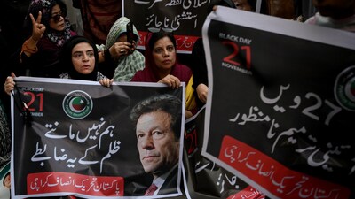 (FILES) Pakistan Tehreek-e-Insaf (PTI) party supporters carry a poster of their leader and former Prime Minister Imran Khan, during a protest against the 27th constitutional amendment, in Karachi on November 21, 2025. (Photo by Rizwan TABASSUM / AFP)