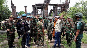 This pool photo taken and released on August 20, 2025 by Agence Kampuchea Presse (AKP) shows Cambodian and foreign military personnel speaking during a visit organized by Cambodia's Ministry of Defence following the CambodiaThailand border conflict at the Preah Vihear temple in Preah Vihear province. (Photo by POOL / AFP)
