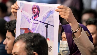 An activist holds a poster of Sharif Osman Hadi, senior leader of the student protest group Inqilab Mancha, who was shot outside a mosque, during a demonstration to condemn the attack in Dhaka on December 15, 2025. (Photo by Munir UZ ZAMAN / AFP)