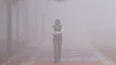 A pedestrian walks through dense fog on a cold winter morning, in New Delhi)