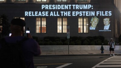 (FILES) People take a photo of an image of US President Donald Trump and Jeffrey Epstein, along with the words - 'President Trump: Release All the Epstein Files', projected onto the US Department of Commerce headquarters on July 18, 2025, in Washington, D.C. 