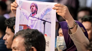 An activist holds a poster of Sharif Osman Hadi, senior leader of the student protest group Inqilab Mancha, who was shot outside a mosque, during a demonstration to condemn the attack in Dhaka on December 15, 2025. (Photo by Munir UZ ZAMAN / AFP)
