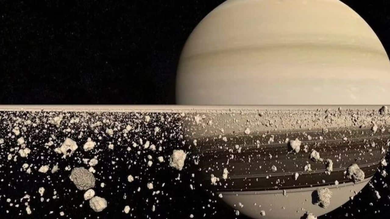 Saturn Rings: The Cassini spacecraft detected harmonic vibrations rippling through Saturn’s rings years ago. In 2026, scientists will be investigating more about their true cause. The gravitational tugs from Saturn’s moons may drive the phenomenon. (Image: Canva)