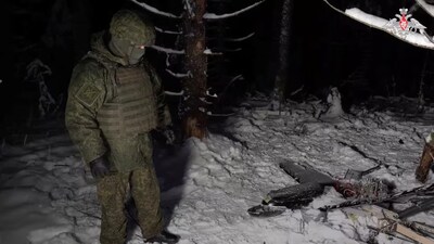 A Russian service member stands next to the remains of a drone, which, according to the Russian Defence Ministry, was downed during the repelling of an alleged Ukrainian attack on the Russian presidential residence in the Novgorod Region. (Image: Reuters)