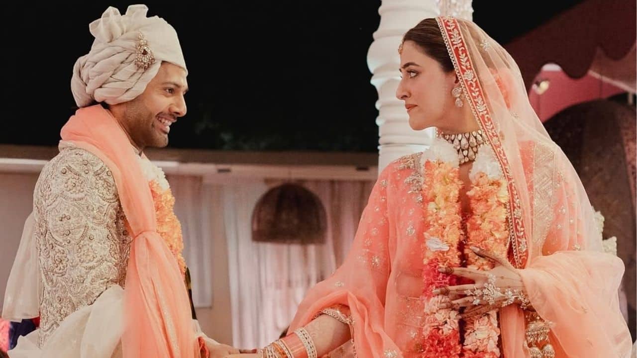 This photograph captures a celebratory highlight as Nupur Sanon and Stebin Ben raise their joined hands in joy. Surrounded by sparkling fireworks and rose petals, the couple beams with happiness. The image beautifully reflects the festive spirit and the beginning of their journey together as husband and wife.