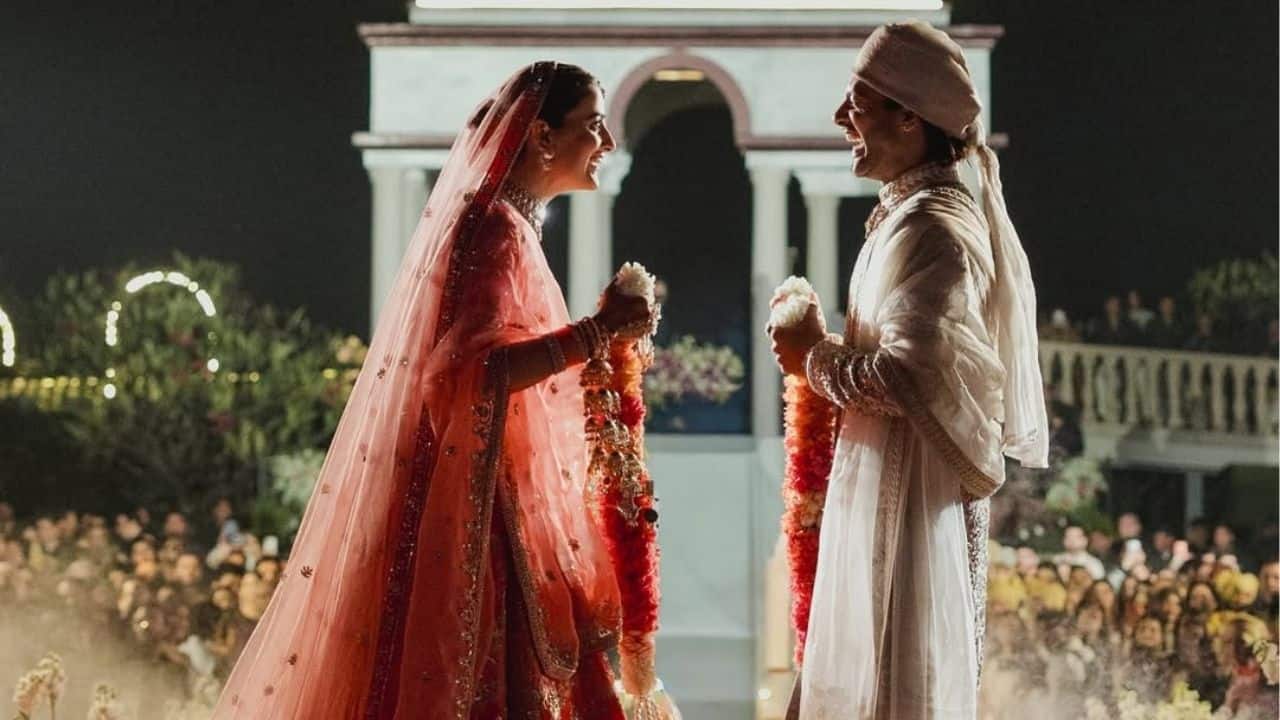 Nupur Sanon and Stebin Ben are seen facing each other during the varmala ceremony, smiling warmly as they hold their garlands. Set against a beautifully lit heritage backdrop, the moment feels intimate and joyful. Their expressions reflect comfort, happiness, and the bond they share.