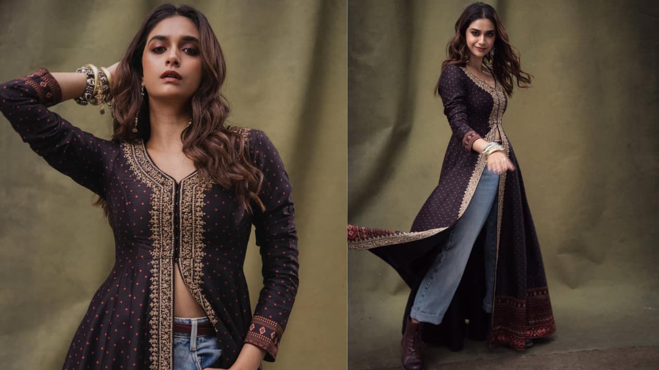 Indo-western glam Keerthy Suresh sports an edgy Indo-Western fusion ensemble that pairs a traditional floor-length tunic with rugged streetwear. The deep navy kurta features a delicate red polka-dot print and is heavily accented with golden zari embroidery along the neckline and high centre slit.