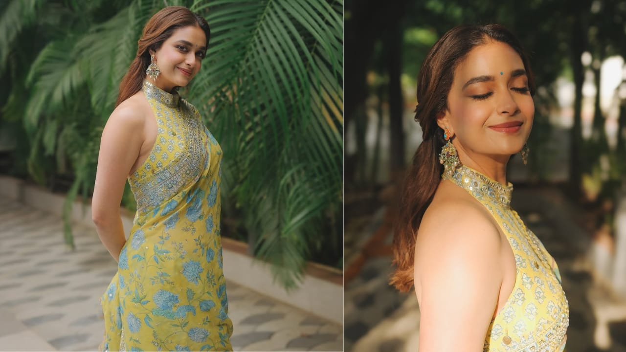 Floral elegance Keerthy transitions to a contemporary floral saree look that feels light and summery. The outfit features a vibrant yellow saree adorned with teal and blue floral motifs, paired with a sophisticated halter-neck blouse.