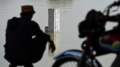 A resident from the nearby neighbourhood looks on the water level scale of river Indus in flood hit Sukkur of Sindh province on August 28, 2022. (Photo by Asif HASSAN / AFP)