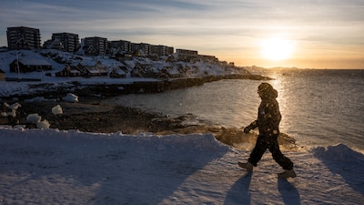 A man walks on the shoreline in Nuuk, Greenland, on January 20, 2026. (Photo by Jonathan NACKSTRAND / AFP)