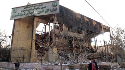 This photograph taken during a tour for foreign media shows women walking past a government building that was burnt during recent public protests, in Tehran on January 21, 2026. (AFP)