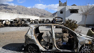 A man stands beside burnt vehicles inside a torched police station on the outskirts of Quetta on February 1, 2026 a day after an attack by Baloch separatists. (Photo by Banaras KHAN / AFP)