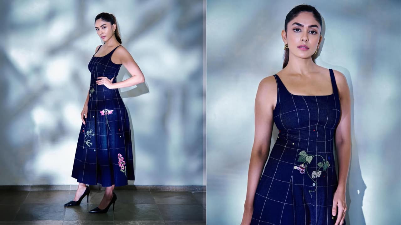 Modern denim midi In this look, Mrunal wears a navy grid-patterned midi dress that reimagines denim. The square-neck silhouette is adorned with delicate floral embroidery, adding a touch of artisanal charm to the structured fabric. With a sleek high ponytail and minimal gold earrings, the outfit feels fresh, youthful, and sophisticatedly understated.