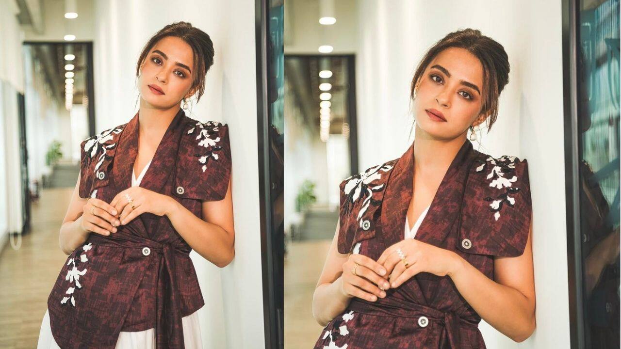 Surveen Chawla keeps it fresh and easy, pairing a breezy white dress with a brown jacket detailed with white and black floral embroidery. The belted waist gives the soft look a flattering, defined shape.