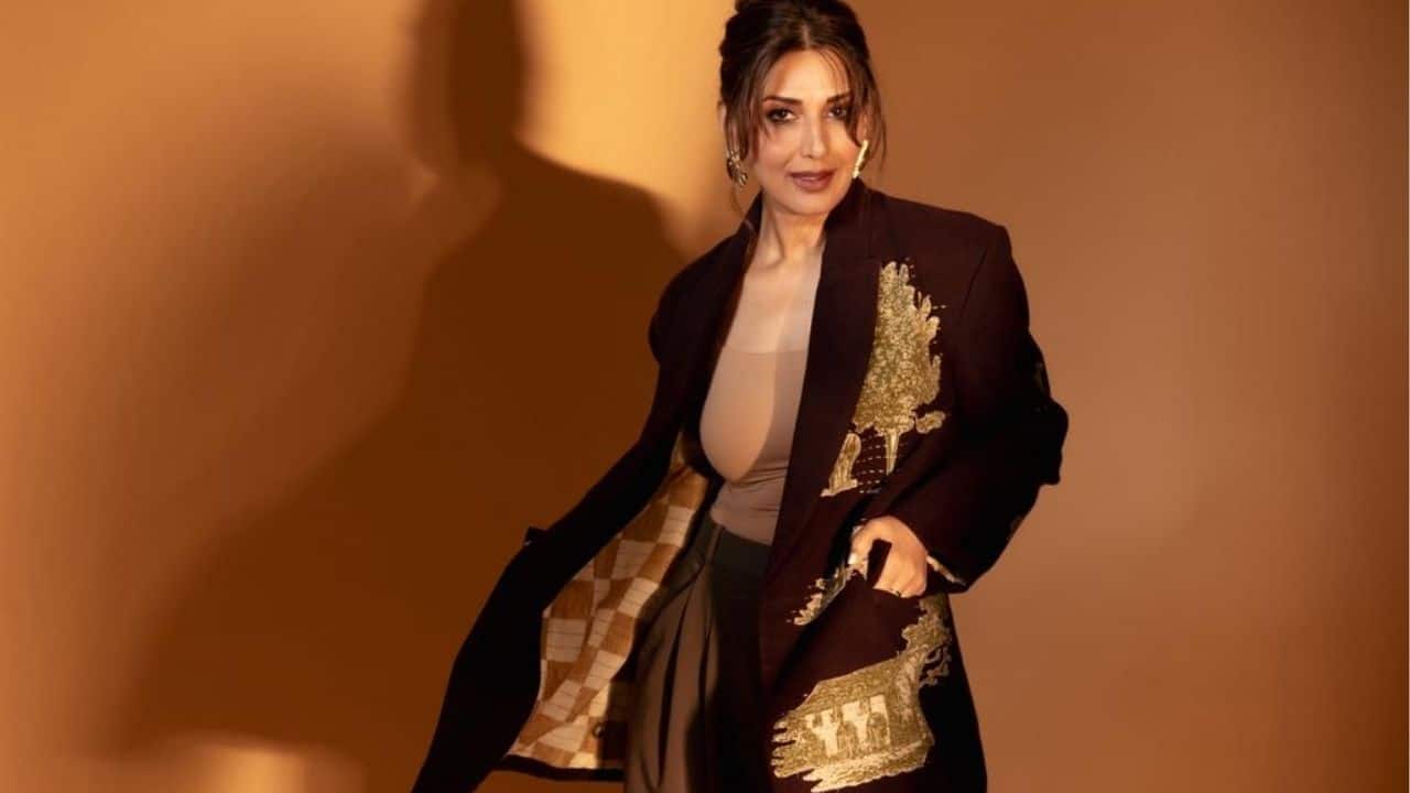 Sonali Bendre opts for timeless sophistication in a monochromatic brown palette, layering a beige fitted top and chocolate trousers under a dark brown coat with gold embroidered patches.