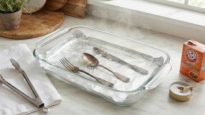 A simple DIY trick involving aluminium foil, baking soda, and hot water can help clean your silverware in minutes (Picture: AI generated)