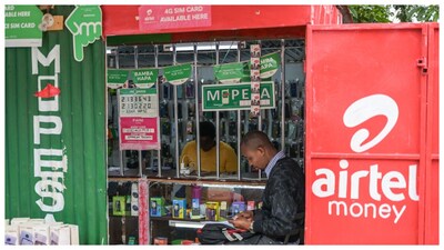 A customer sits at a kiosk next to a sign advertising  Airtel mobile money service. (Courtesy: Reuters file photo)