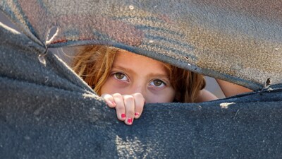 A displaced girl looks through a covering made from blankets at a tent camp sheltering displaced Palestinians in Khan Younis, in the southern Gaza Strip, July 20, 2026. REUTERS/Ramadan Abed
