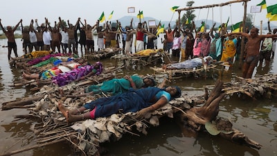 Protesters and members of families affected by the Ken-Betwa River Link Project lie on symbolic funeral pyres placed in the water, while others stand beneath a wooden frame with symbolic nooses around their necks during a protest near the Majhgawan Dam on the Ken River in Ajaygarh, Madhya Pradesh, India, September 20, 2026. REUTERS/Amit Dave