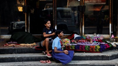 A girl braids another girl's hair as she gets ready for school by the roadside early morning in Kolkata, India, November 13, 2024. REUTERS/Sahiba Chawdhary