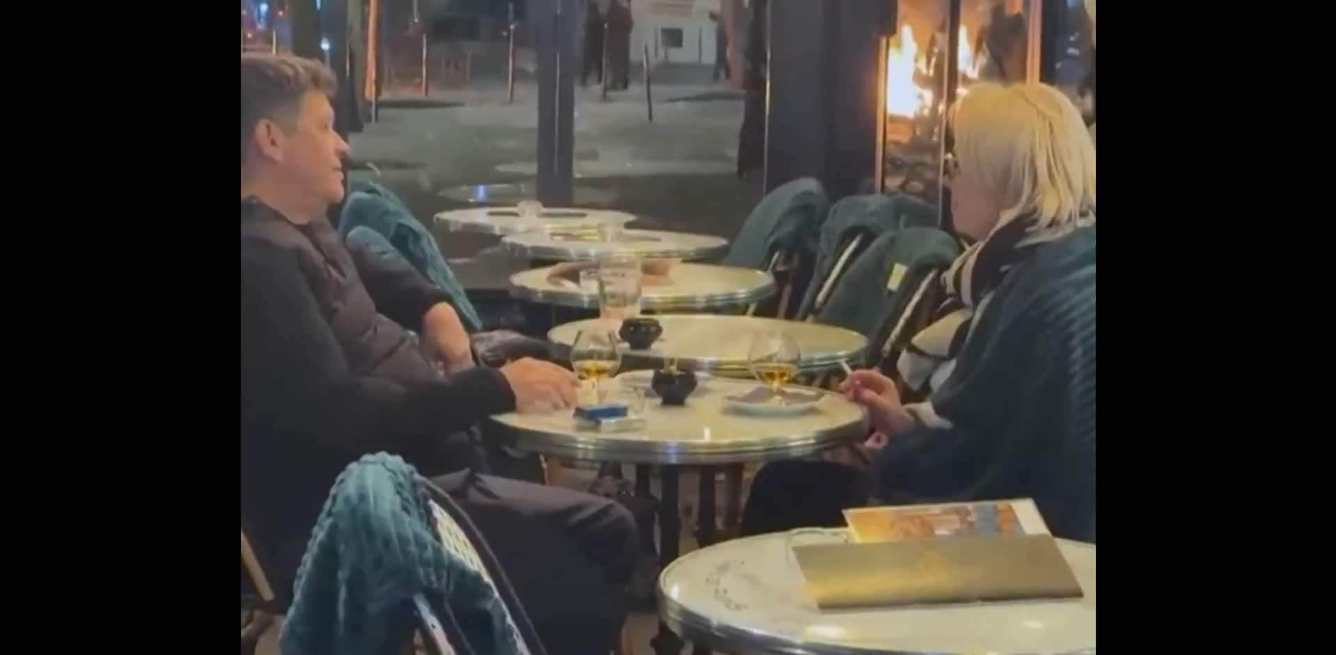 Wine, cigarettes and a burning Paris: Couple casually enjoys cafe date amid violent protests