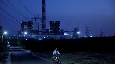 FILE PHOTO: A woman cycles past the NTPC power plant in Solapur, India. Reuters